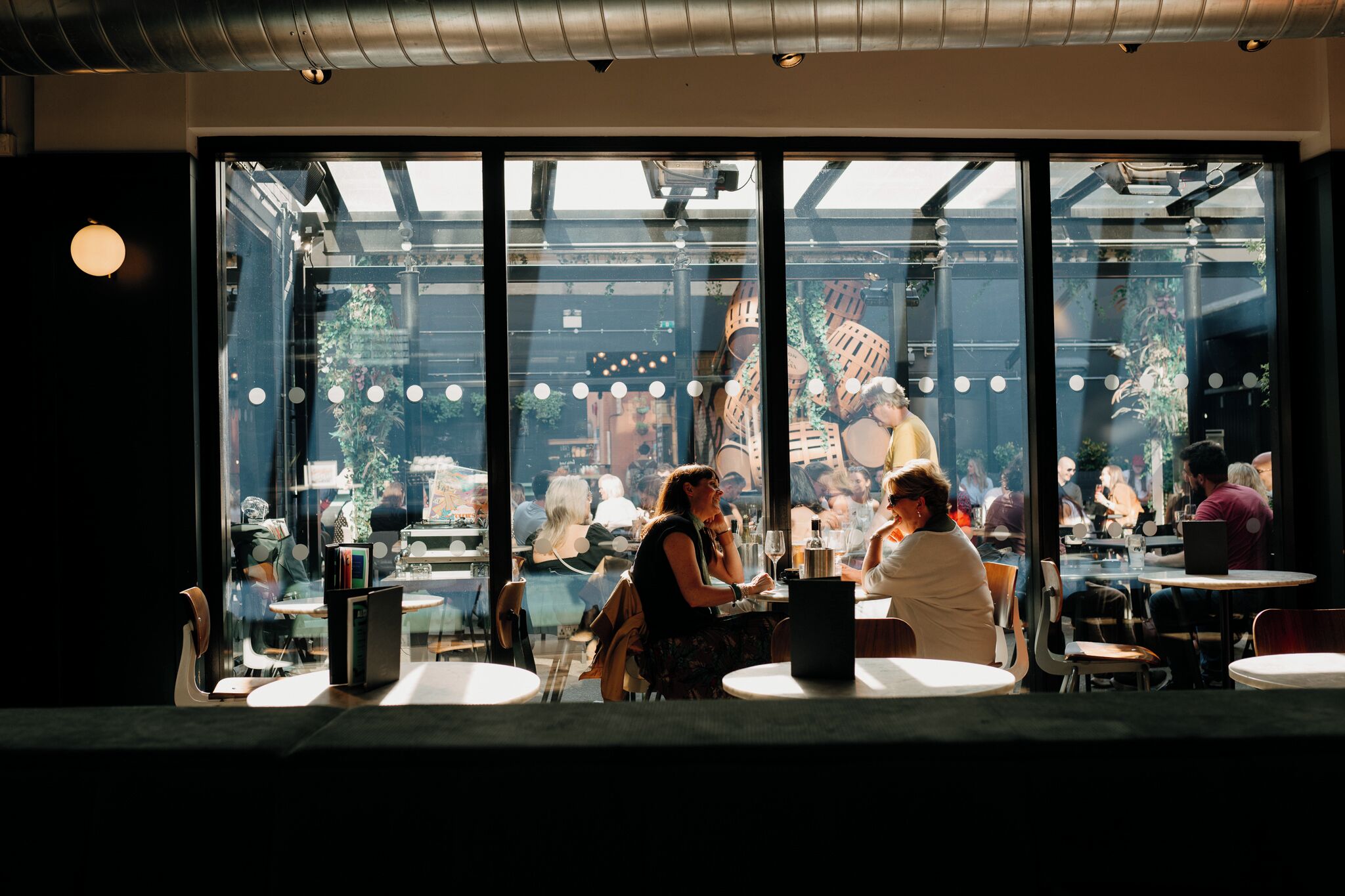 An indoor dining area with large windows, tables, and chairs.