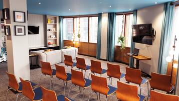 A conference room with a white sofa, a TV mounted on the wall, and a laptop on a table.