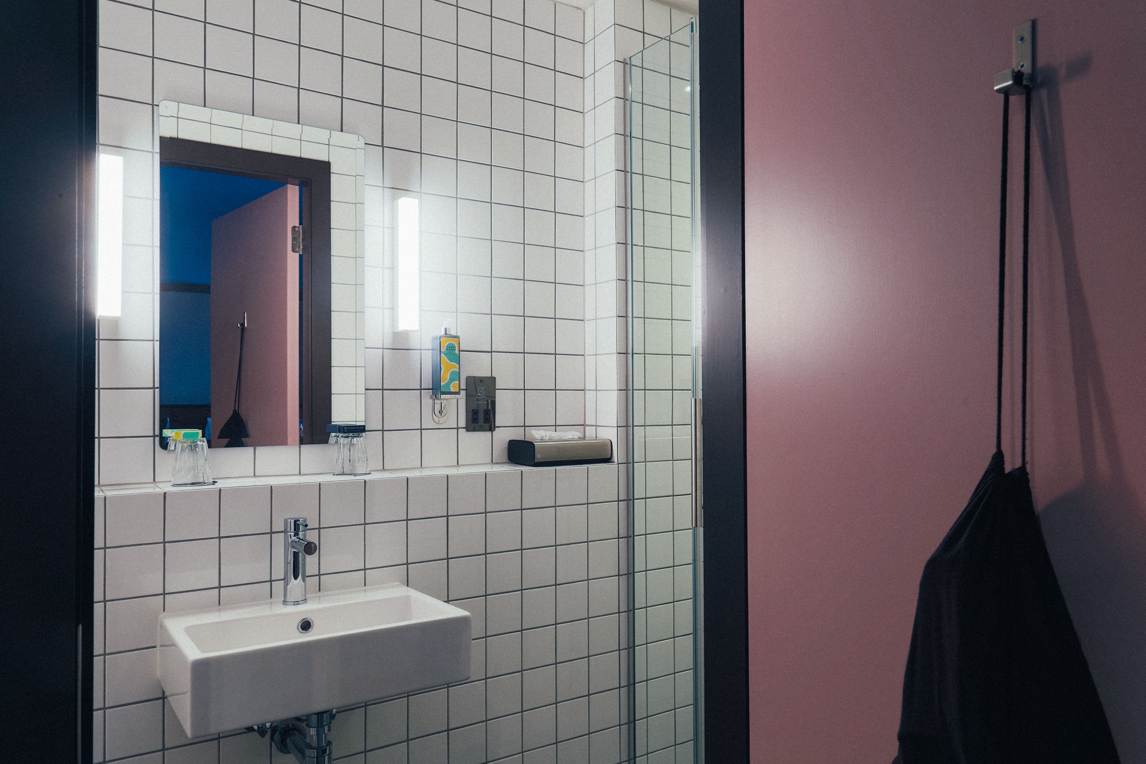 Un baño con lavamanos blanco, espejo y cabina de ducha de vidrio.