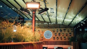 A cozy indoor seating area with a wooden wall, a ceiling with string lights, and a sign that reads "MALFY GIN ITALY". - Bullitt Hotel (Belfast)