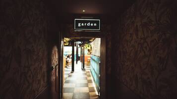 A hallway with a sign reading 'garden' leading to an outdoor area with tables and chairs.