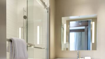 A modern bathroom with a glass shower enclosure, a white sink, and a mirror above the sink.