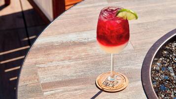 A cocktail glass with a lime garnish on a wooden coaster labeled "USER DECK" on a table.