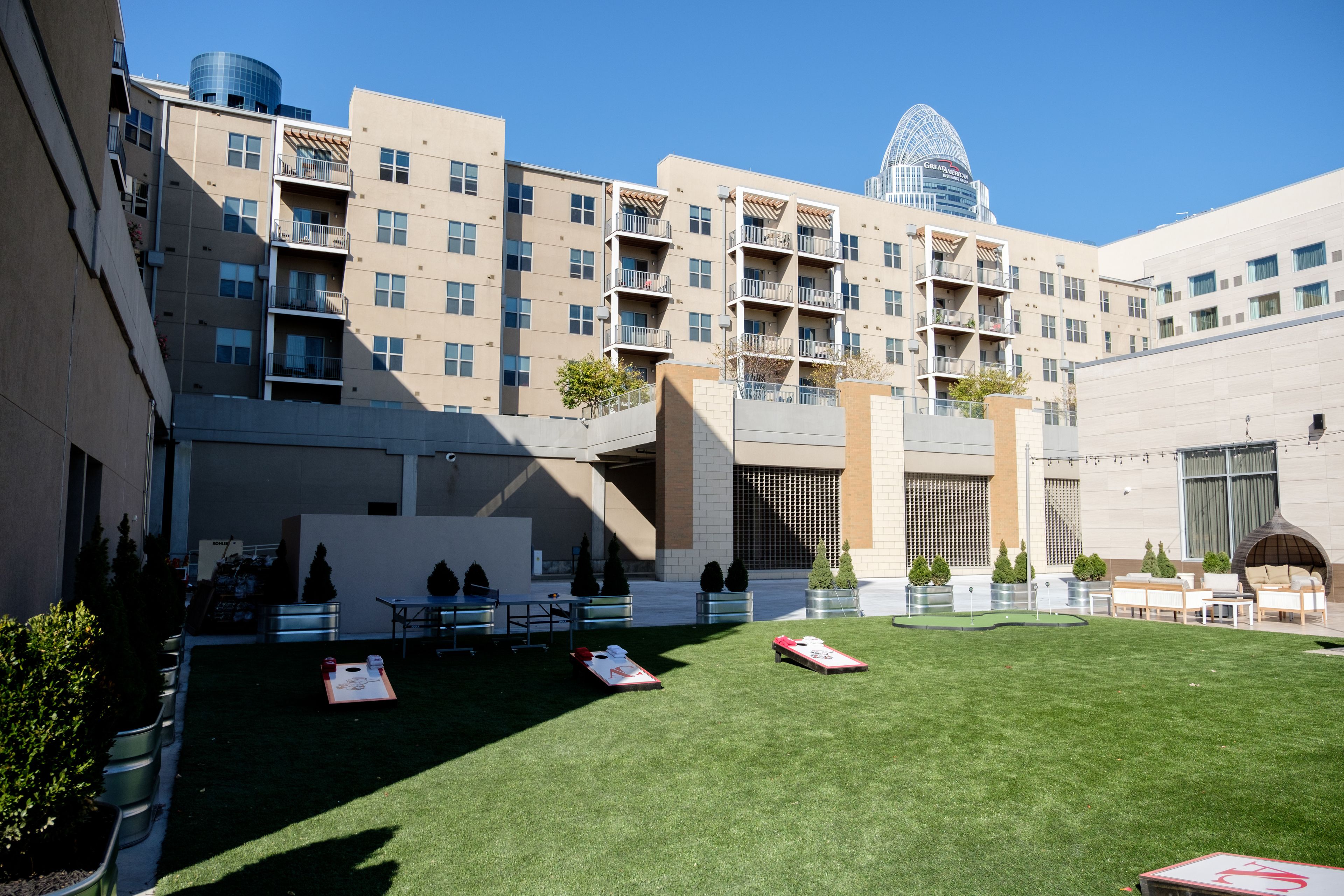 A courtyard with a lawn, outdoor seating, and a building with multiple floors and balconies.