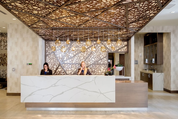 Een receptie met een marmeren balie, een decoratief plafond en hangende lampen.