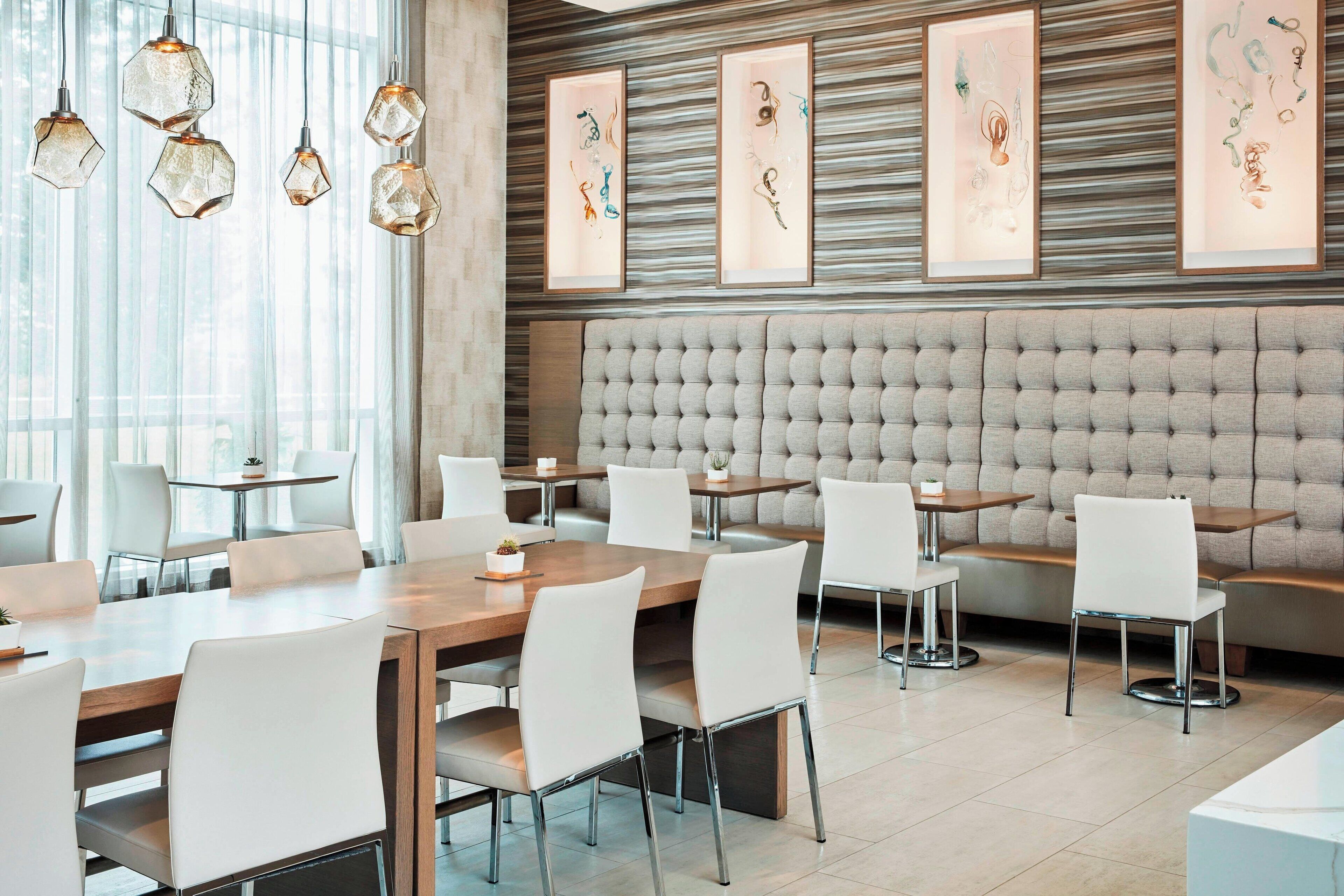 A modern dining area with hexagonal pendant lights, framed artwork on the wall, and a tufted headboard.
