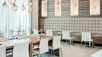 A modern dining area with hexagonal pendant lights, framed artwork on the wall, and a tufted headboard.