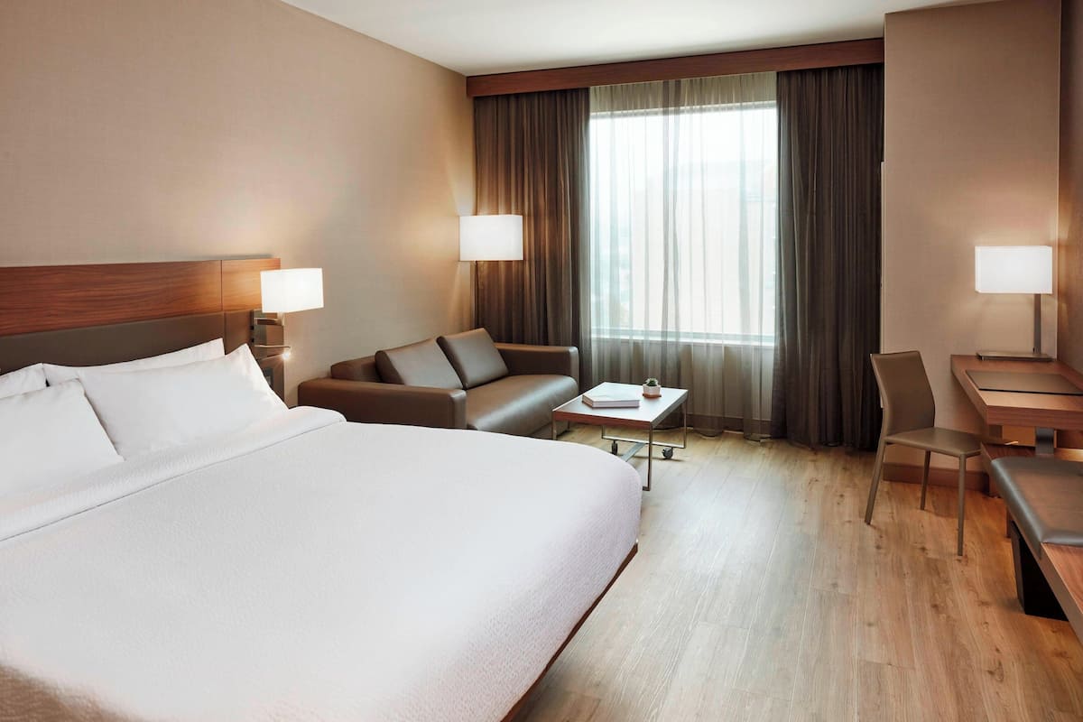 Ein Hotelzimmer mit einem großen Bett, einer Couch, einem Schreibtisch und zwei Lampen.