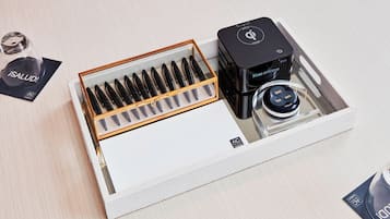 A tray with a set of black pens, a black device labeled "KUBE SYSTEMS," and a small container with a lid.