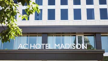 Exterior del Hotel AC Madison con una fachada moderna, amplias ventanas y un letrero llamativo.