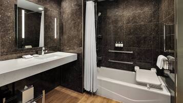 A modern bathroom with a large mirror, a white bathtub, and a shower area.