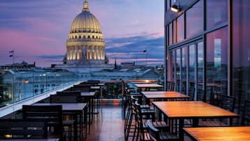 A rooftop terrace with tables and chairs, overlooking a large domed building with classical architecture.