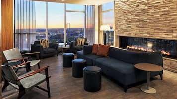 A modern lounge area with a sofa, chairs, ottomans, and a fireplace.
