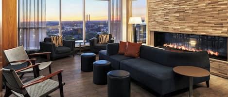 A modern lounge area with a sofa, chairs, ottomans, and a fireplace.