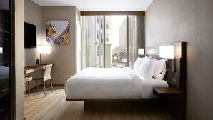 A modern hotel room with a large bed, a desk, a chair, a flat-screen TV, and a city view. - AC Hotel Raleigh North Hills (Raleigh)