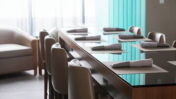 A modern conference room with a glass table, leather chairs, and a teal accent wall.