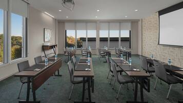 A conference room with tables, chairs, and a projector screen.