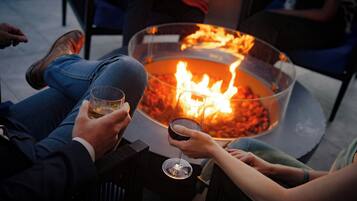 People sitting around a fire pit with glasses of wine.