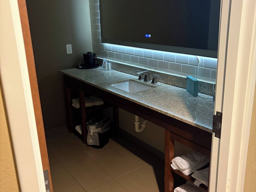 A bathroom with a large mirror, a sink, and a towel rack.