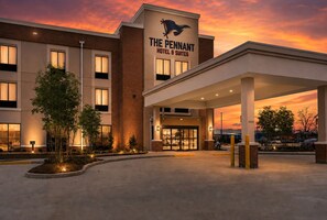 A hotel with a prominent sign, a covered entrance, and a landscaped area with trees.