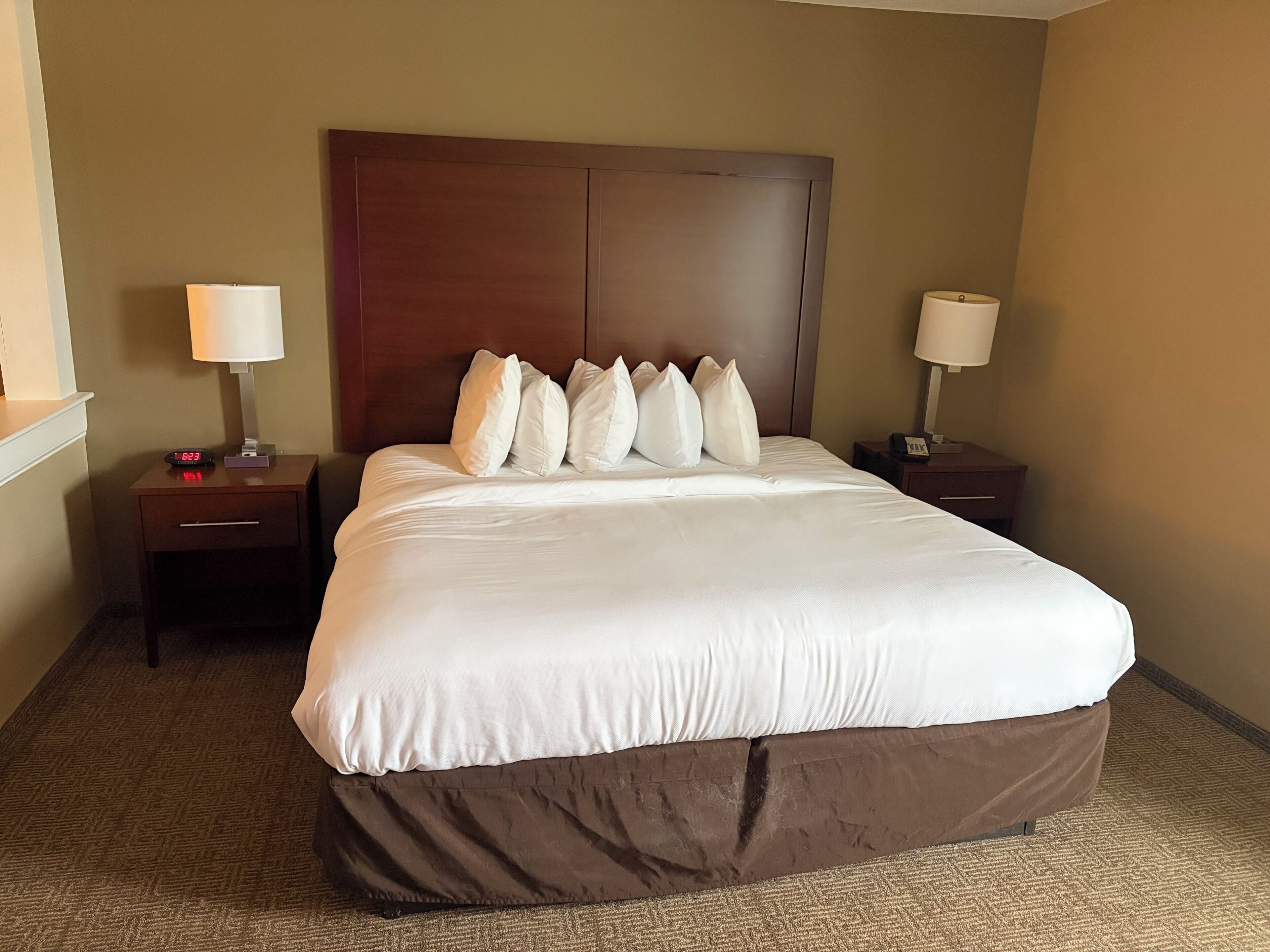 Quarto de hotel com uma cama grande, duas mesas de cabeceira e uma cabeceira.