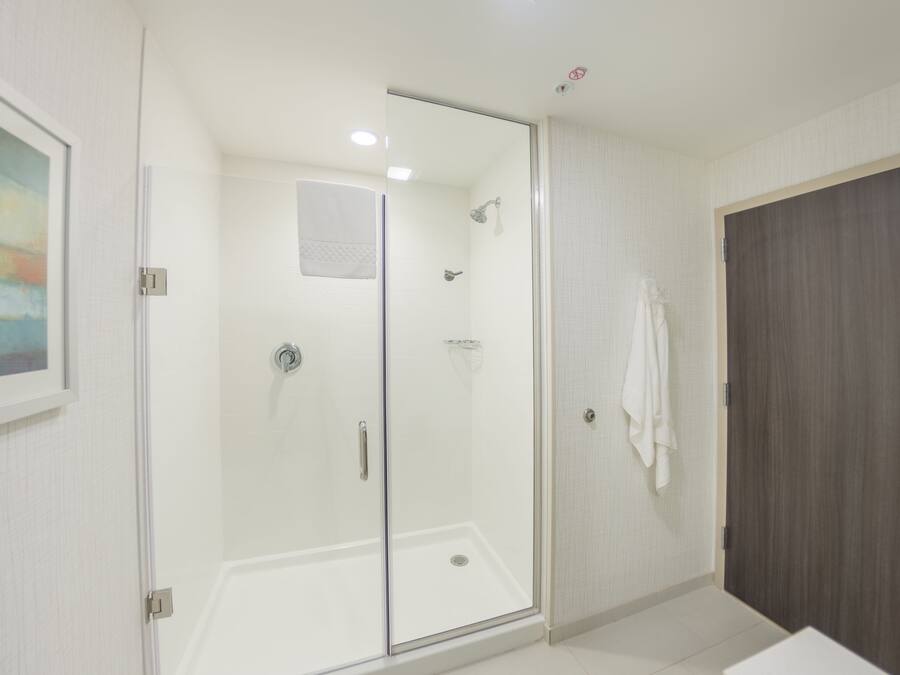A modern bathroom with a glass-enclosed shower, a white sink, and a dark wooden door.