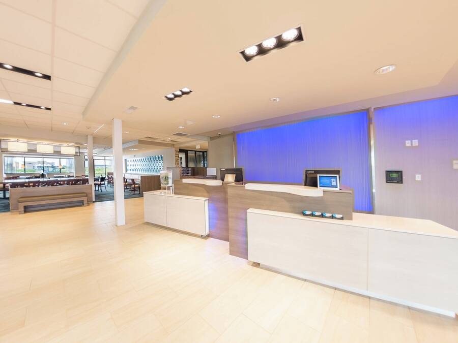 Eine geräumige Lobby mit Empfangstresen, Sitzgelegenheiten und einem großen Fenster mit Blick ins Freie.