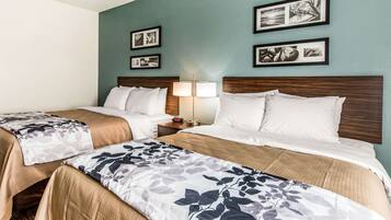 A hotel room with two beds, a nightstand with a lamp, and framed pictures on the wall.