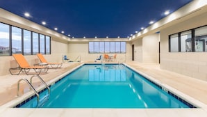 Una piscina con sillas de descanso y vistas a la ciudad.