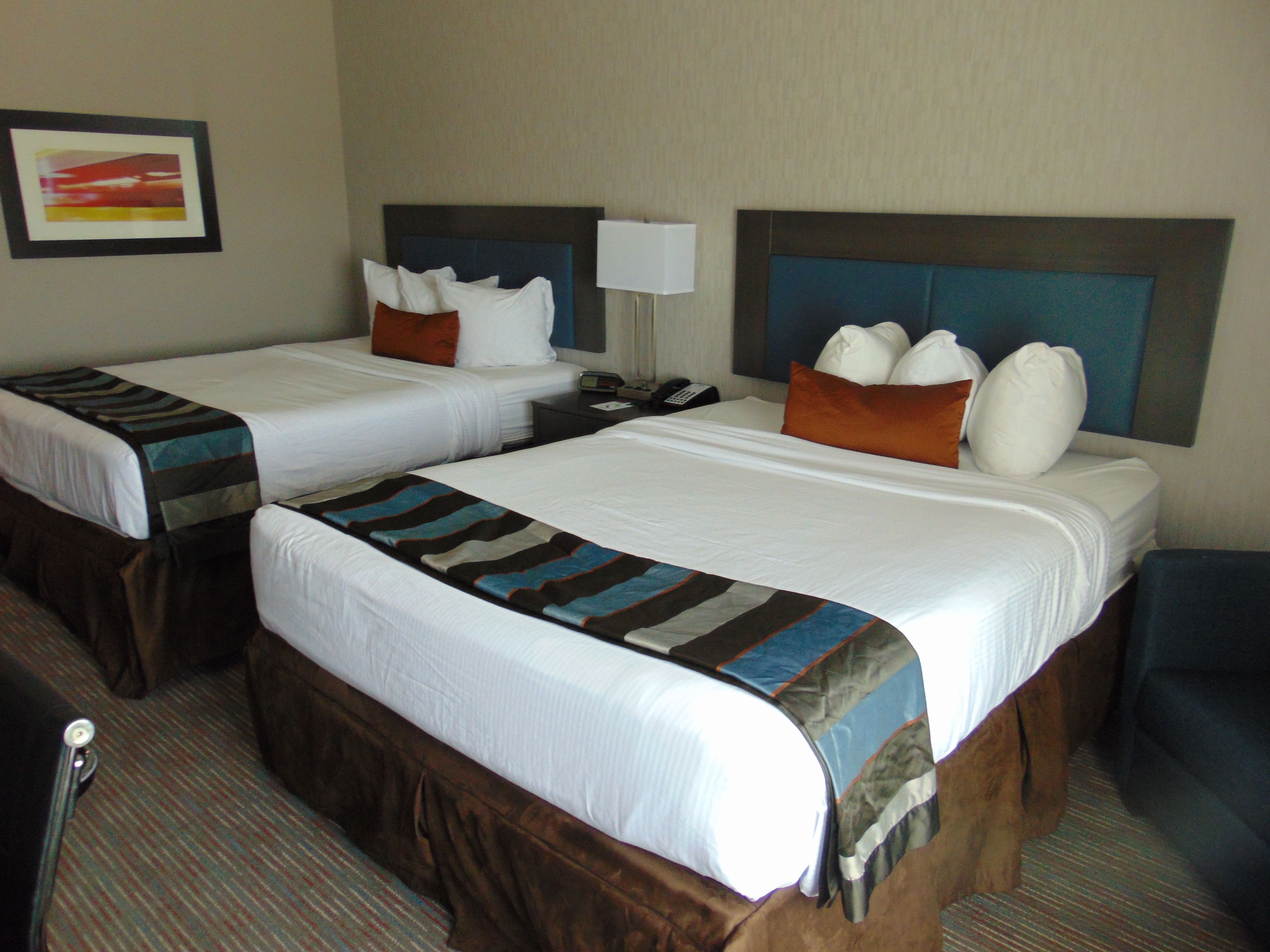 A hotel room with two beds, each with a headboard, a bedside lamp, and a telephone.