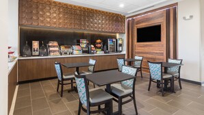 Un restaurante con mostrador, mesas y una televisión.