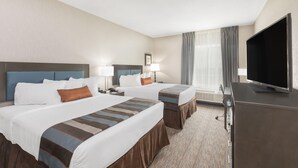 Habitación de hotel con dos camas, televisor de pantalla plana, escritorio y ventana con cortinas.