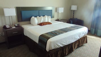 A hotel room with a large bed, two bedside tables, a nightstand, a telephone, and two lamps.