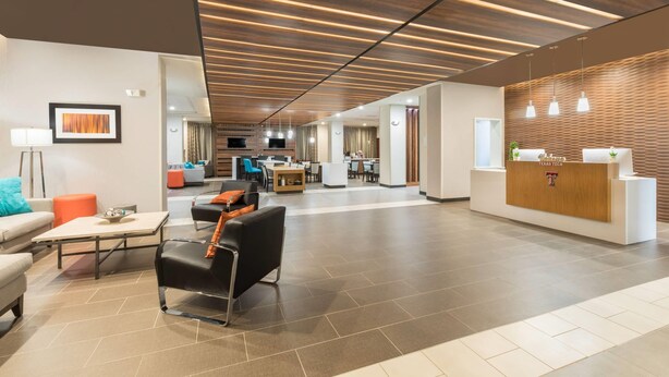 Un lobby amplio con mostrador de recepción, zona de estar y un diseño de techo moderno.