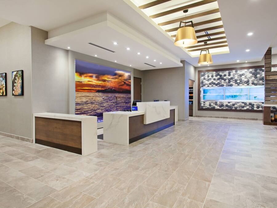 A modern reception area with a large mural of a sunset over water, a reception desk, and a seating area with a patterned wall.