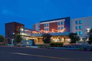 Un hotel moderno con un letrero llamativo que dice "Springhill Suites Marriott". Tiene una estructura de varios pisos con fachadas de vidrio y ladrillo.