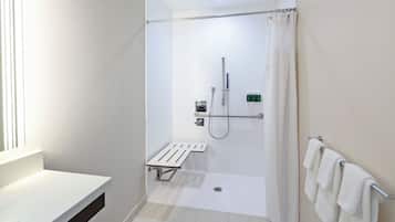 A modern bathroom with a shower, a white sink, and a towel rack.
