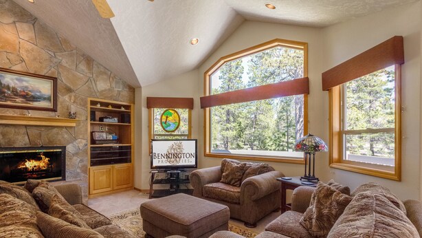 A cozy living room with a stone fireplace, large windows, and a comfortable seating area. - Sparks 7 (Bend)