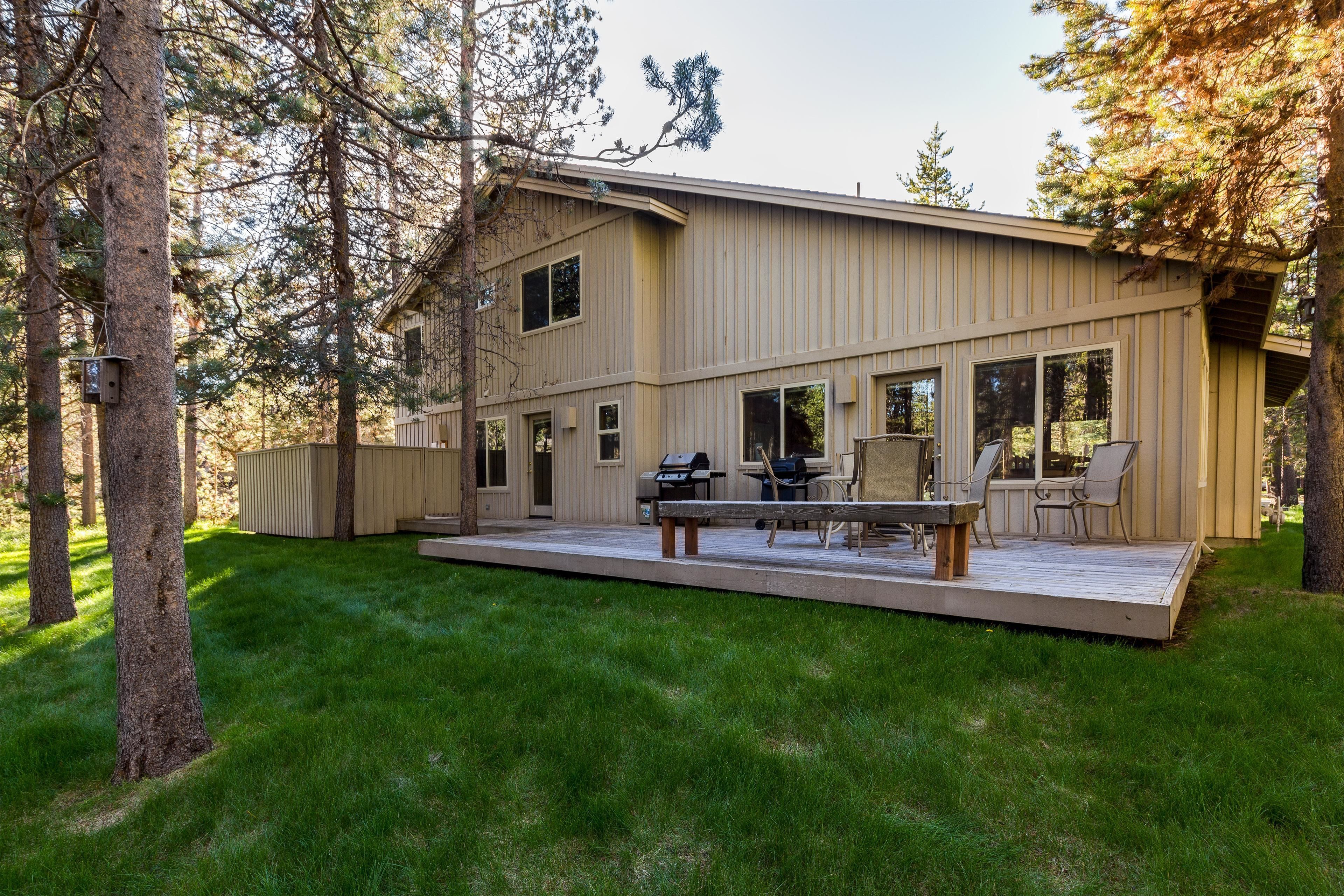 A two-story house with a deck, a barbecue grill, and a covered patio area.