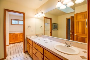 A bathroom with two sinks, wooden cabinets, a large mirror, and a patterned floor. - Gosling 5 (Bend)