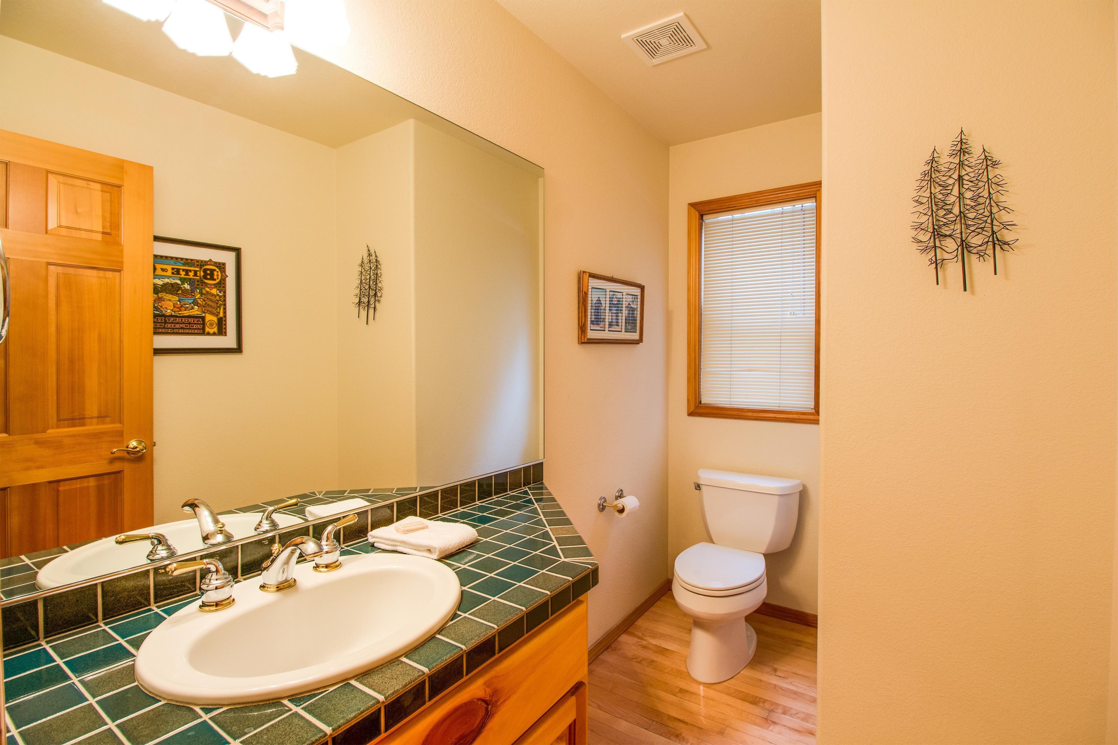 A bathroom with a green-tiled sink, a wooden door, and a white toilet.