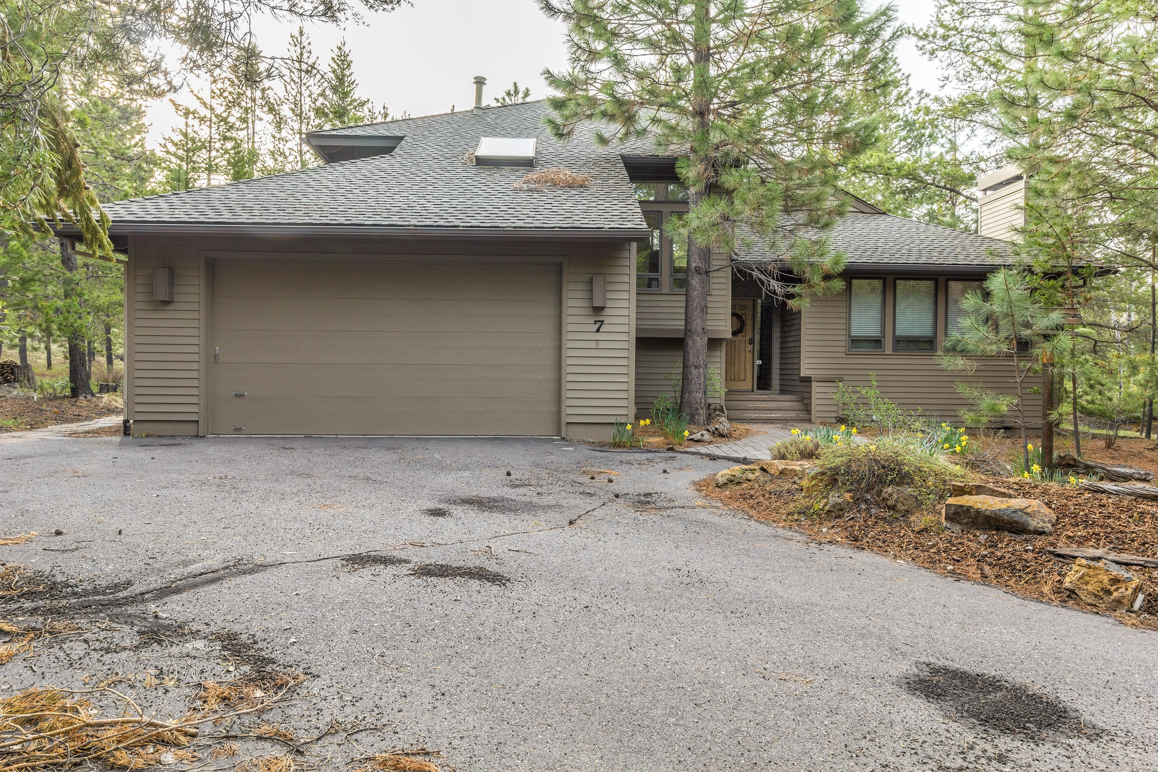A two-story house with a garage, a covered driveway, and a small porch.