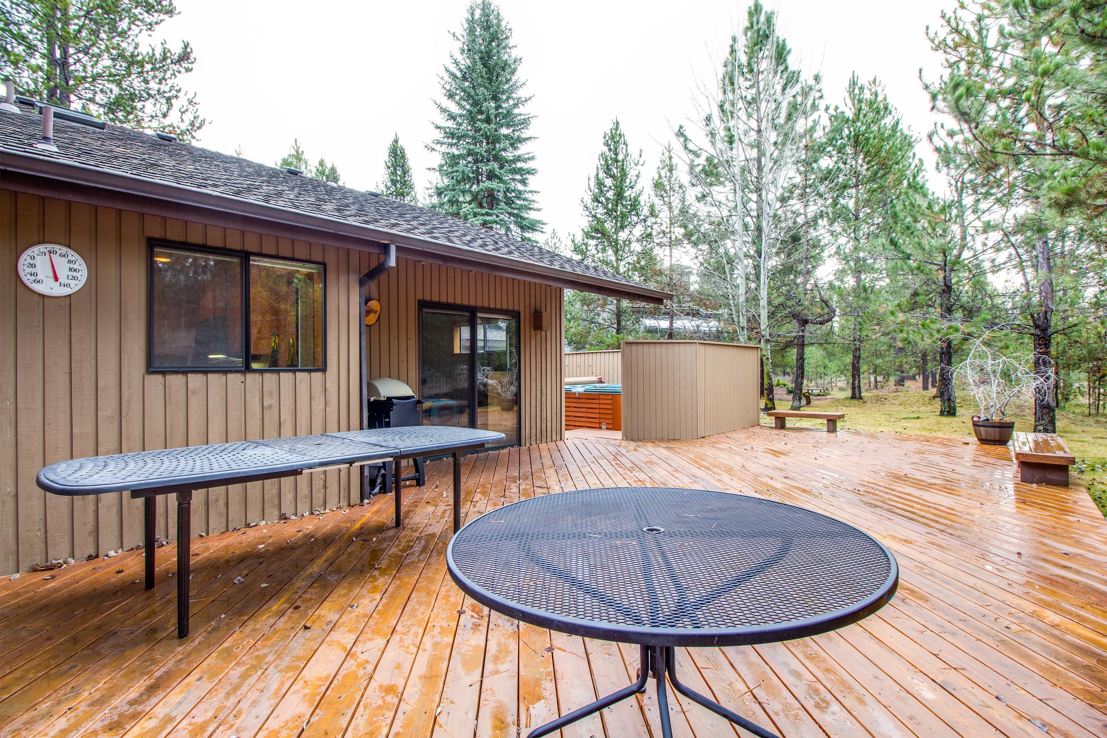 A wooden deck with two tables and a clock on the wall.