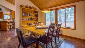 A dining area with a wooden table, chairs, and a bookshelf. - Hoodoo 3 (Bend)