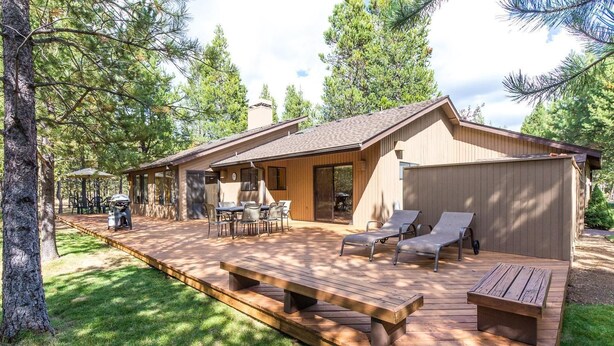 A wooden deck with picnic tables and lounge chairs, surrounded by trees. - Hoodoo 3 (Bend)