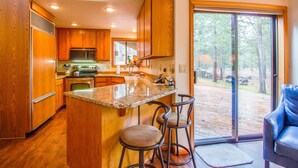 A kitchen with wooden cabinets, a granite countertop, and a large window. - Hoodoo 3 (Bend)
