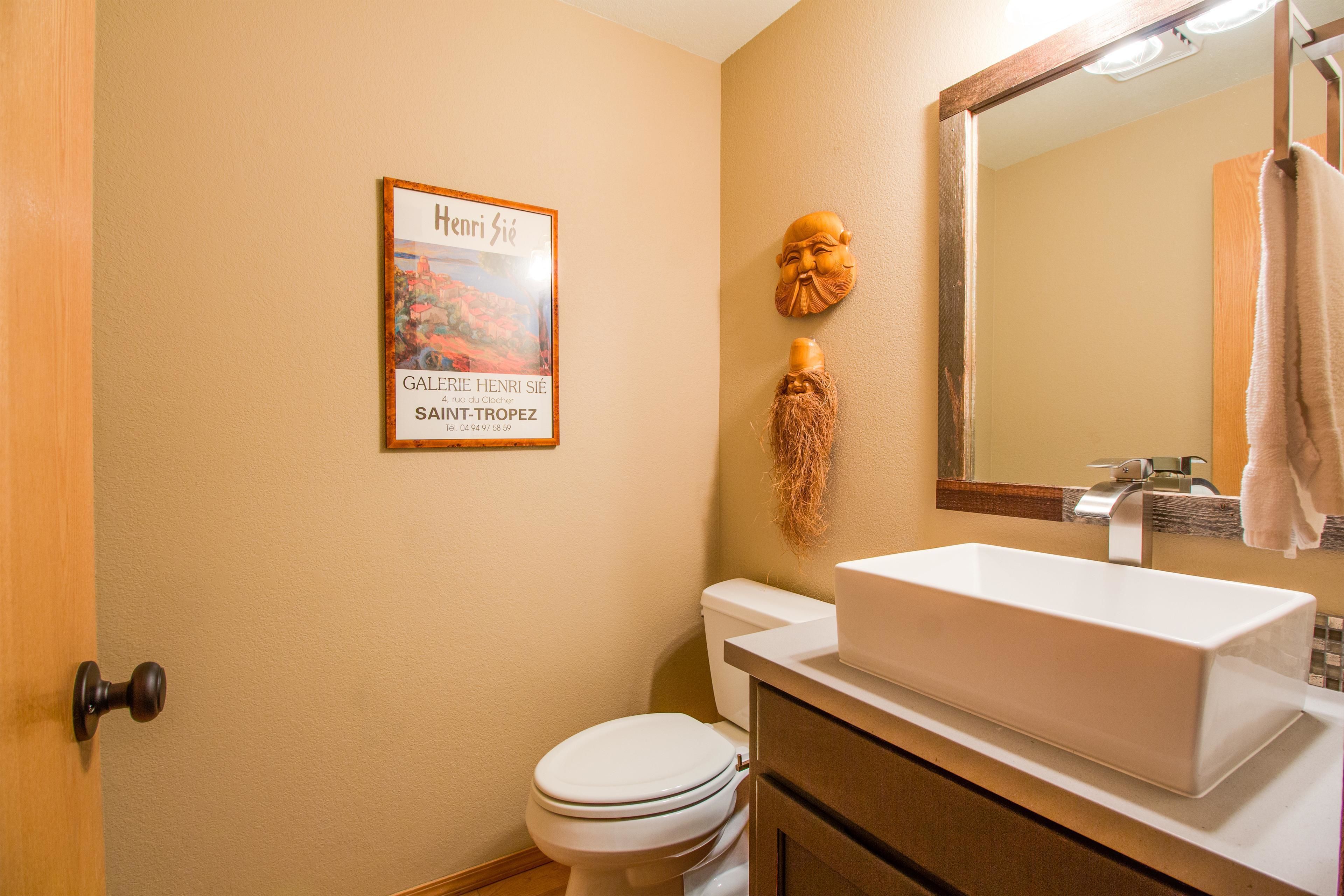 A bathroom with a white toilet, a rectangular sink, and a mirror above it.