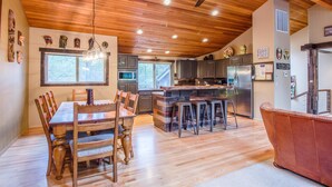 A spacious kitchen with wooden cabinetry, a central island with stools, and a ceiling fan. - Hoodoo 5 (Bend)
