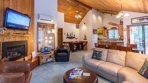 Una sala de estar acogedora con chimenea, sofá de cuero y televisor.