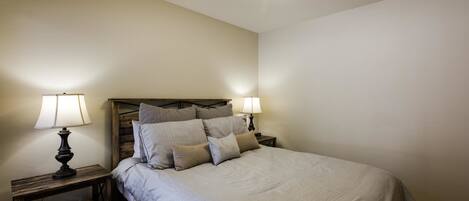 A bedroom with a bed, two bedside tables with lamps, and a ceiling light fixture.